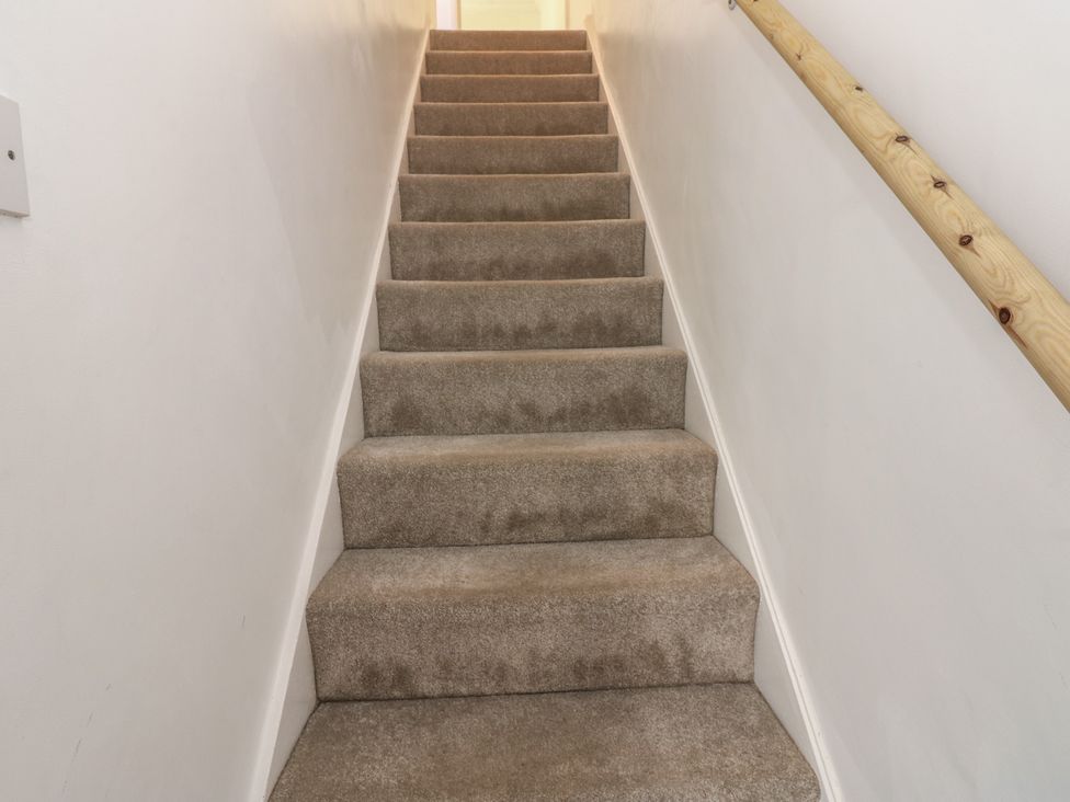 A stairwell with carpeted stairs and a wooden handrail at Lonsdale Street