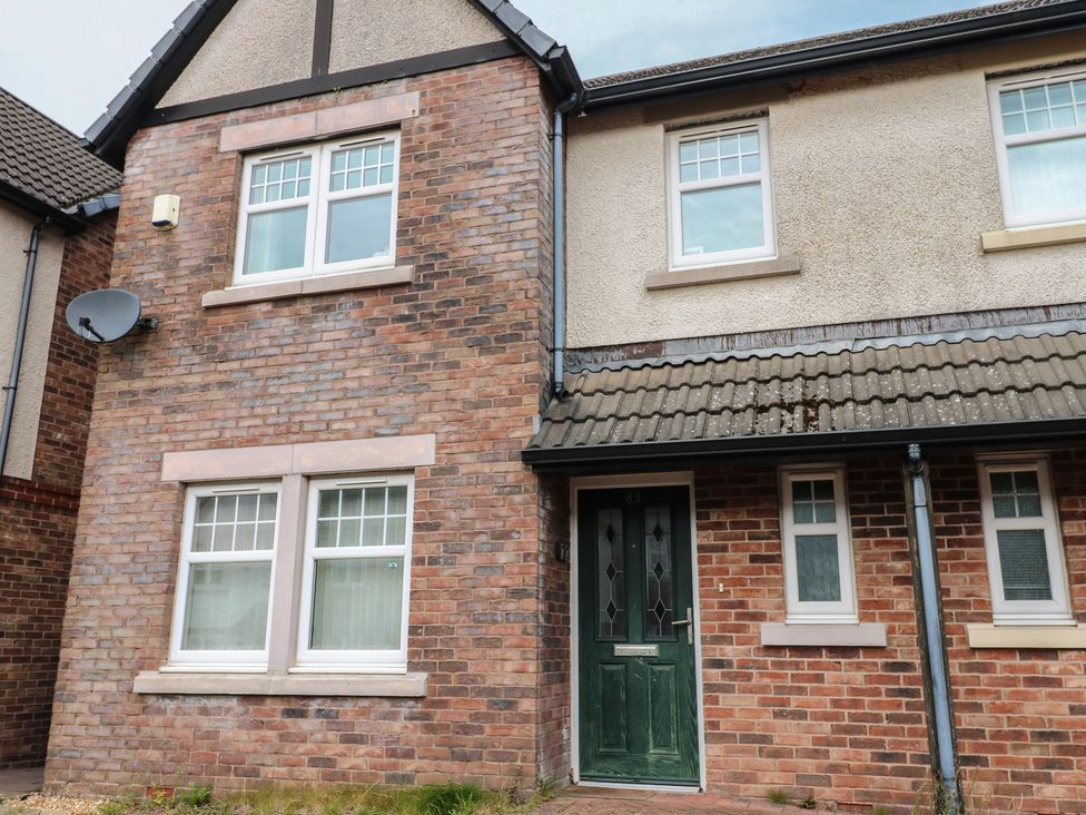 A house exterior with a green door and brick walls at Lingla House in Frizington