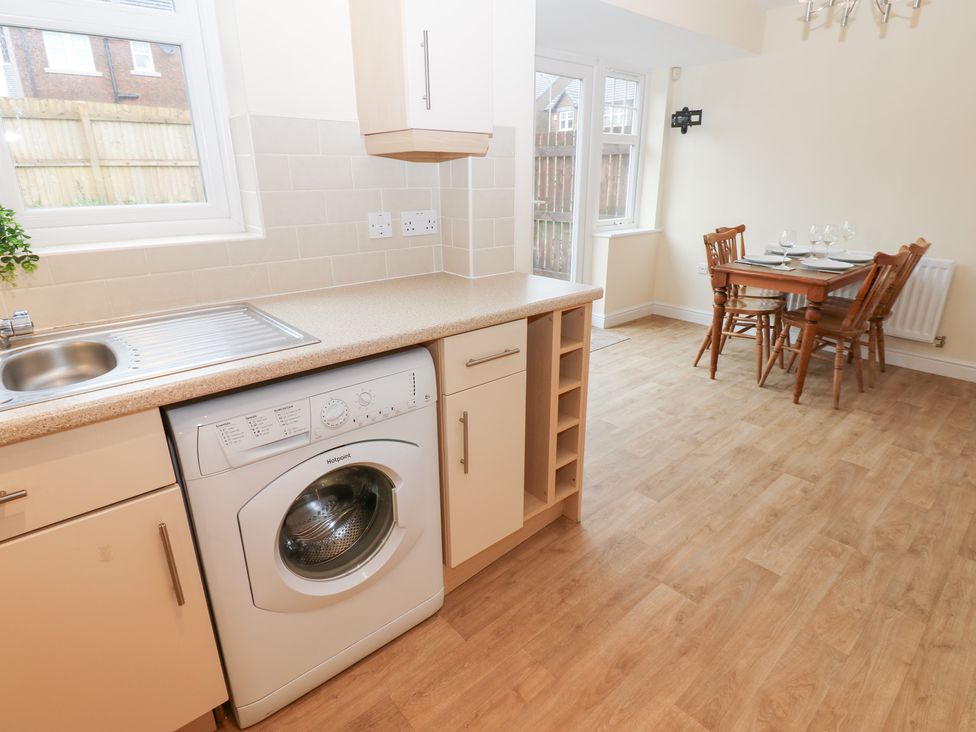 A kitchen with a washing machine and dining area at Lingla House in Frizington
