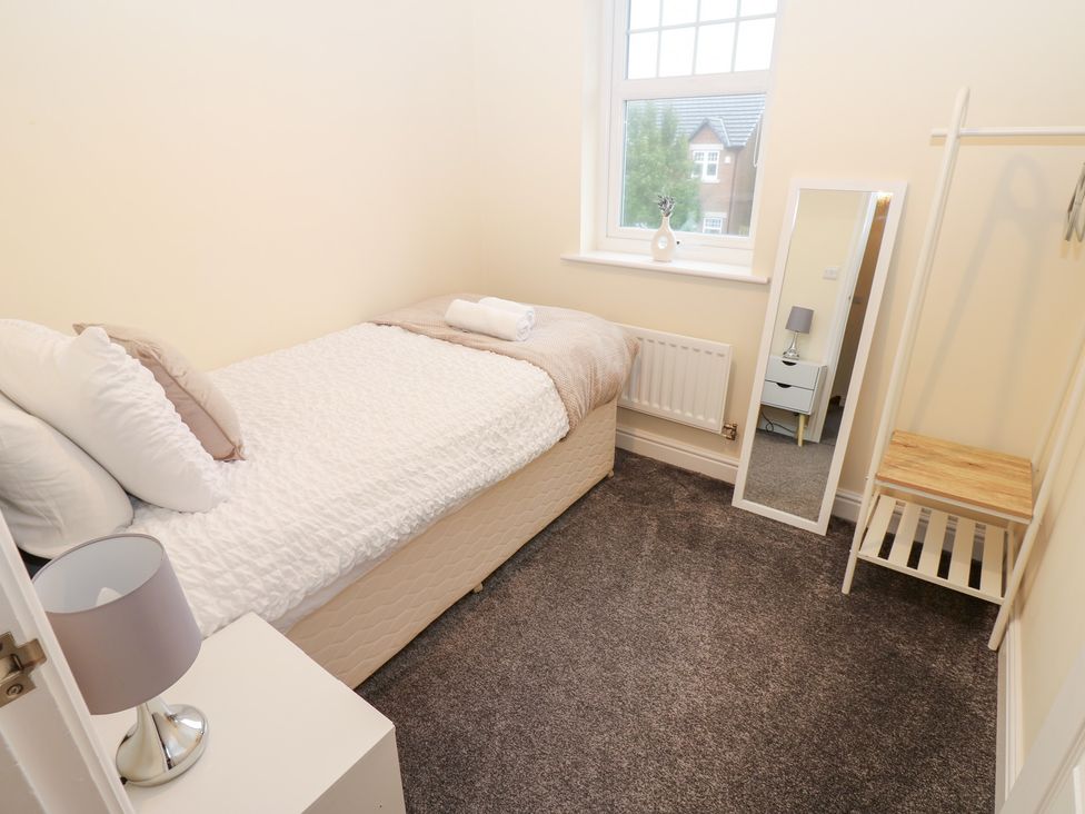 A bedroom with a single bed and a mirror at Lingla House in Frizington