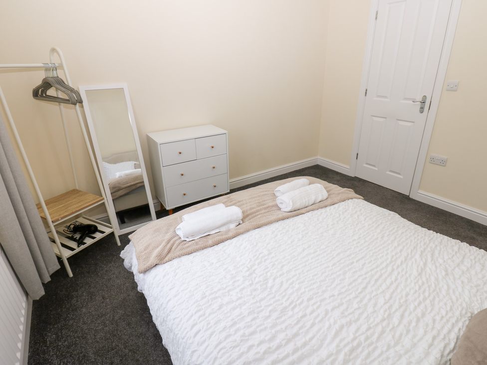 A bedroom with a bed and a dressing mirror at Lingla House in Frizington