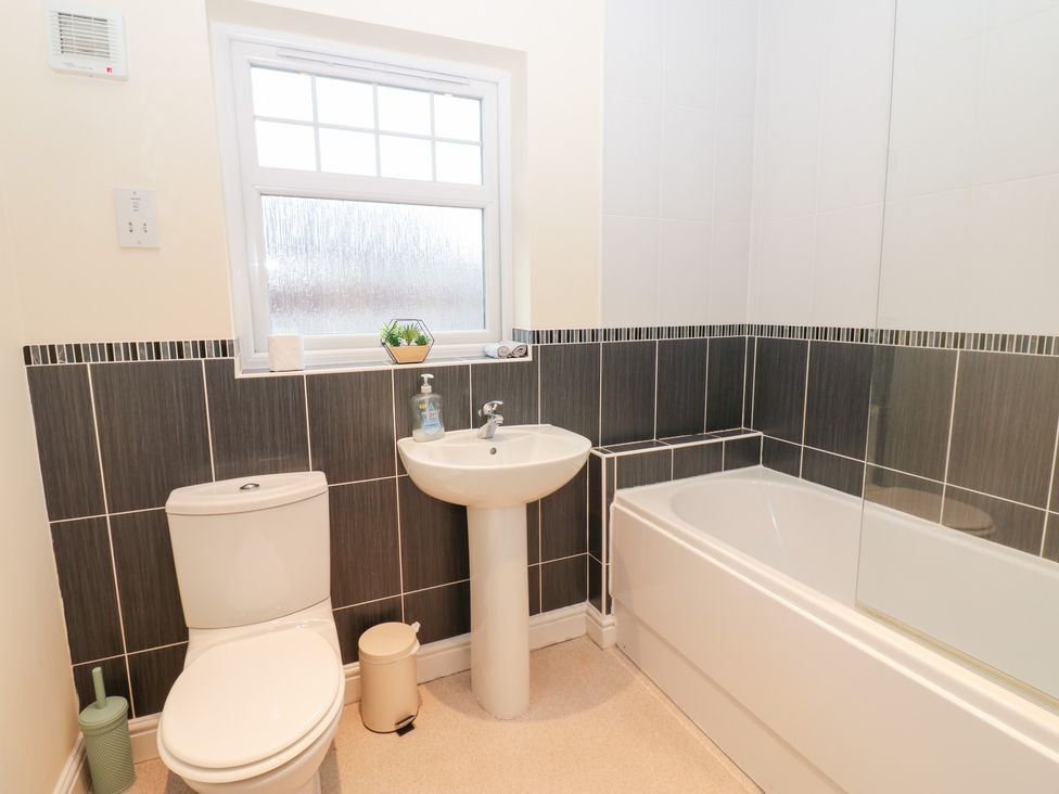 A bathroom with a toilet, sink, and bath at Lingla House in Frizington