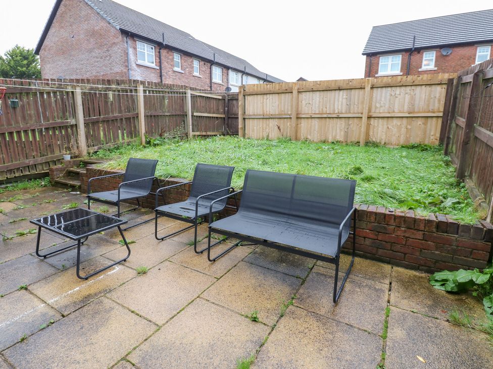 A garden with patio furniture and a fence at Lingla House in Frizington