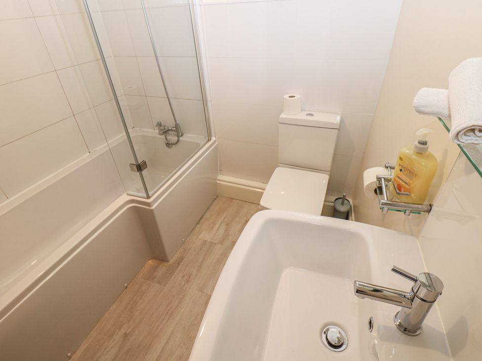 A bathroom with a bath tub, toilet, and sink at Kirkgate Cottage in Cockermouth