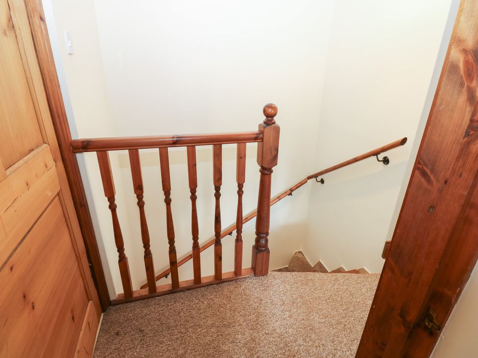 A staircase with a wooden handrail at Kirkgate Cottage in Cockermouth
