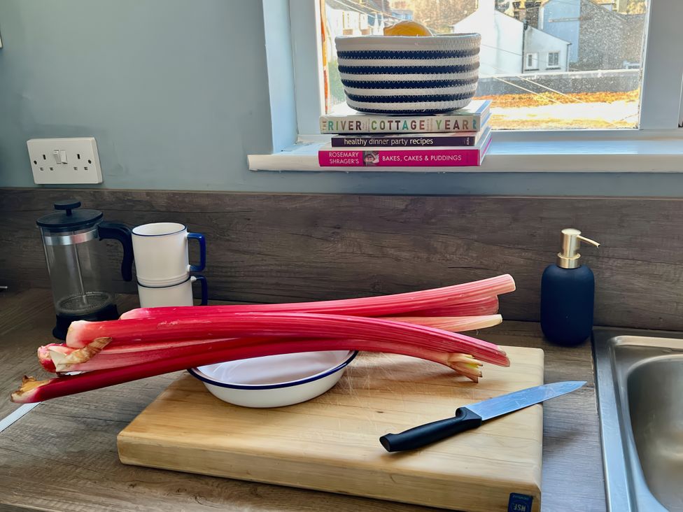 A kitchen counter with rhubarb, a knife, and cookbooks at Corner View in Broadstairs