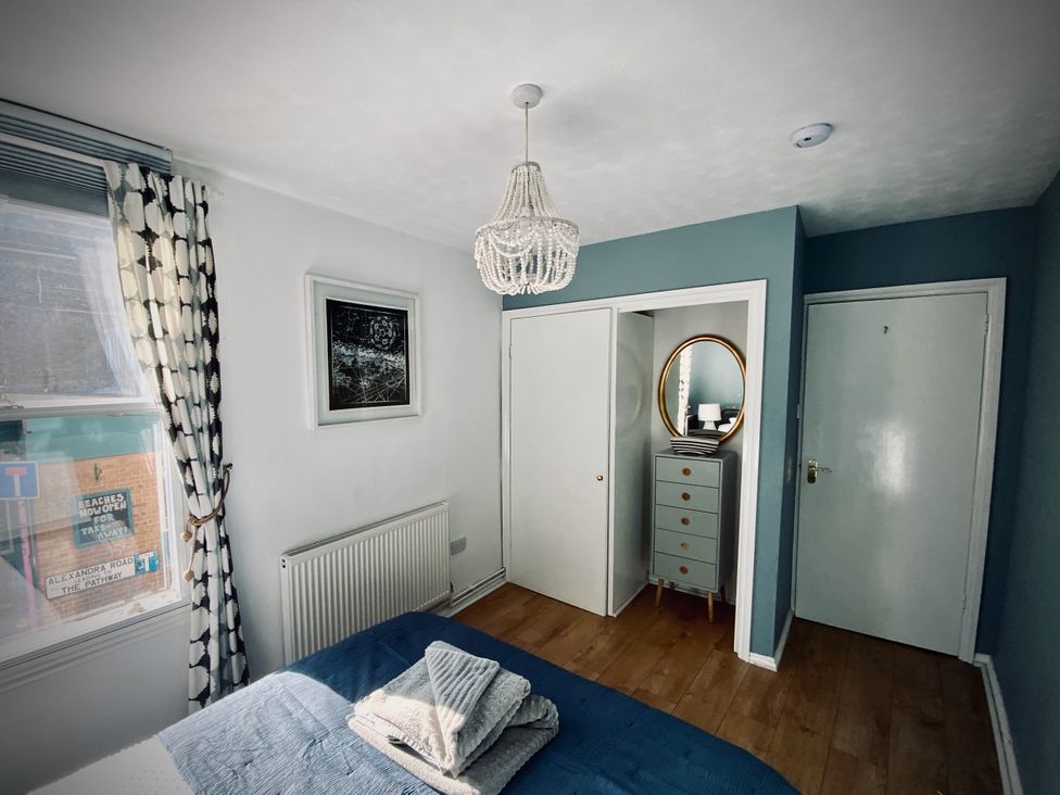 A bedroom with a window, mirror and chest of drawers at Corner View in Broadstairs