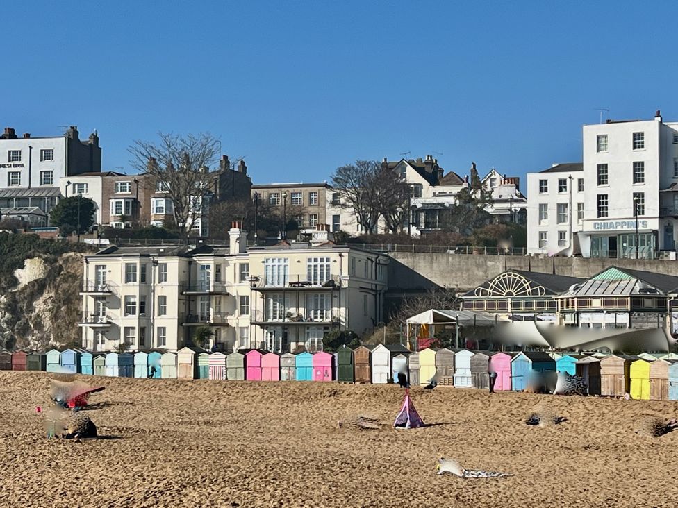 A beach with colorful beach huts and buildings in the background at Corner View in Broadstairs