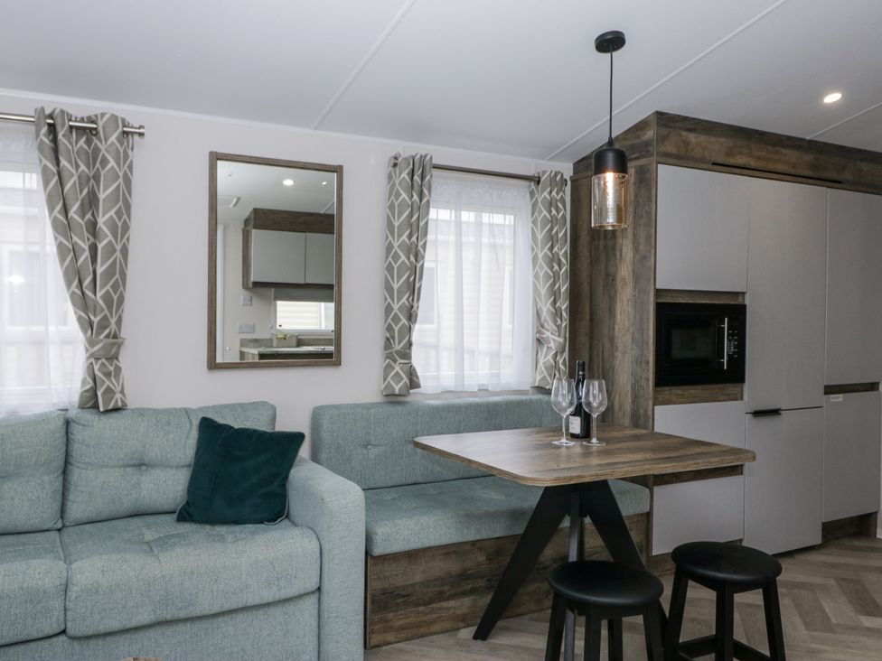 A living room with a sofa and dining area at Puffin in St Bees