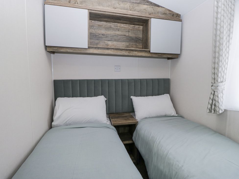 A bedroom with two beds and a shelf at Puffin in St Bees