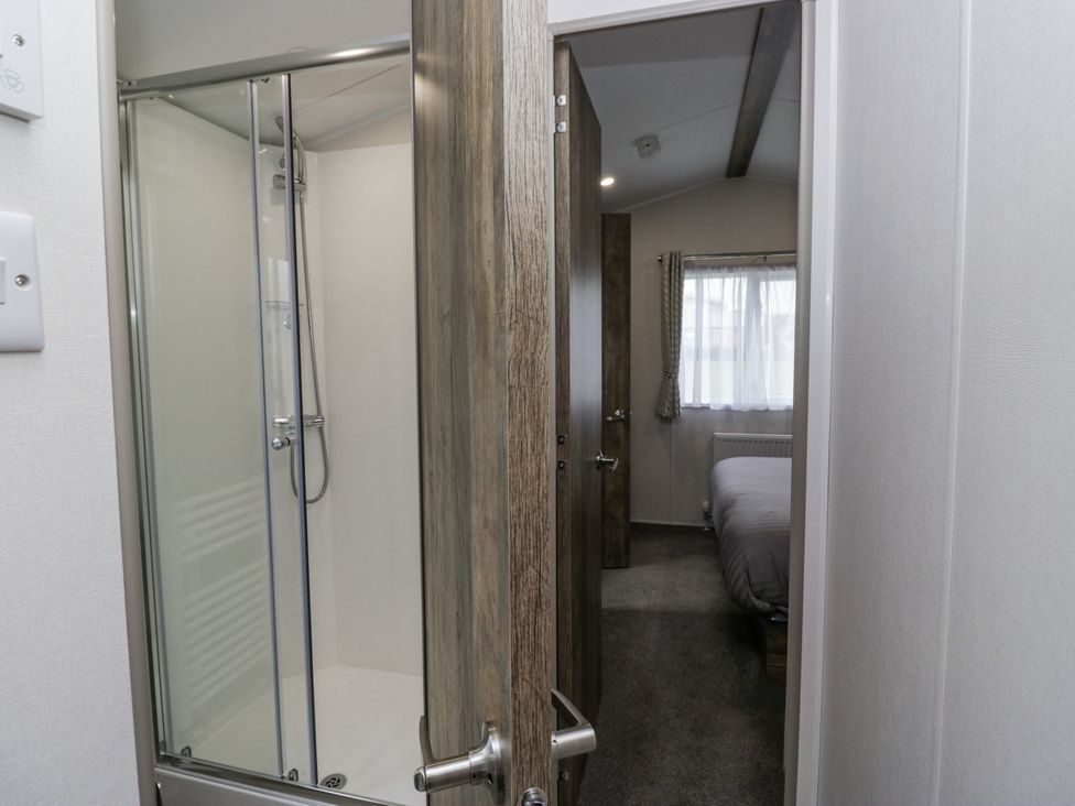 A bathroom with a shower and a view of a bedroom at Puffin in St Bees