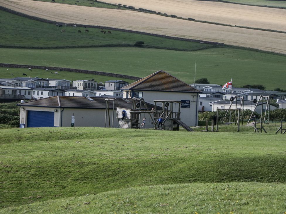 A playground structure with a building and caravans at Puffin St Bees