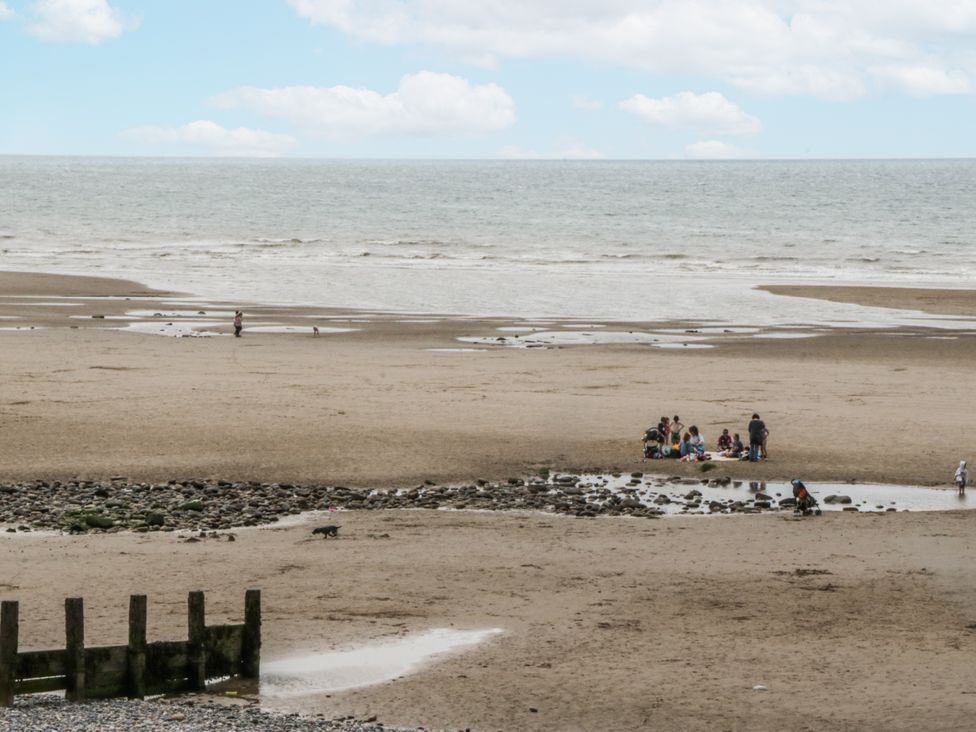A beach with people by the water at Puffin in St Bees