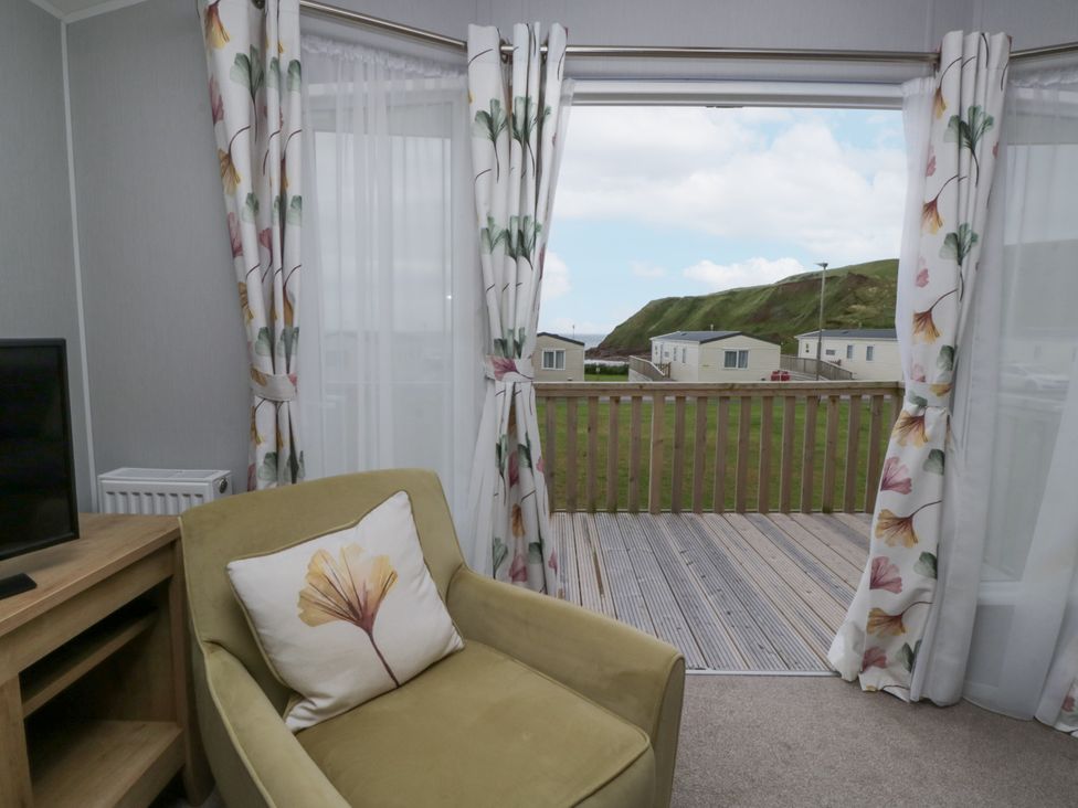 A living room with a chair and television at Sandpiper in St Bees