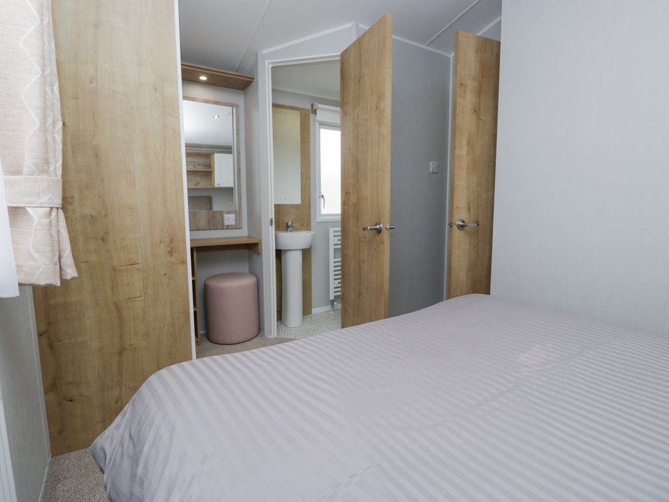 A bedroom with a bed and a bathroom area at Sandpiper in St Bees