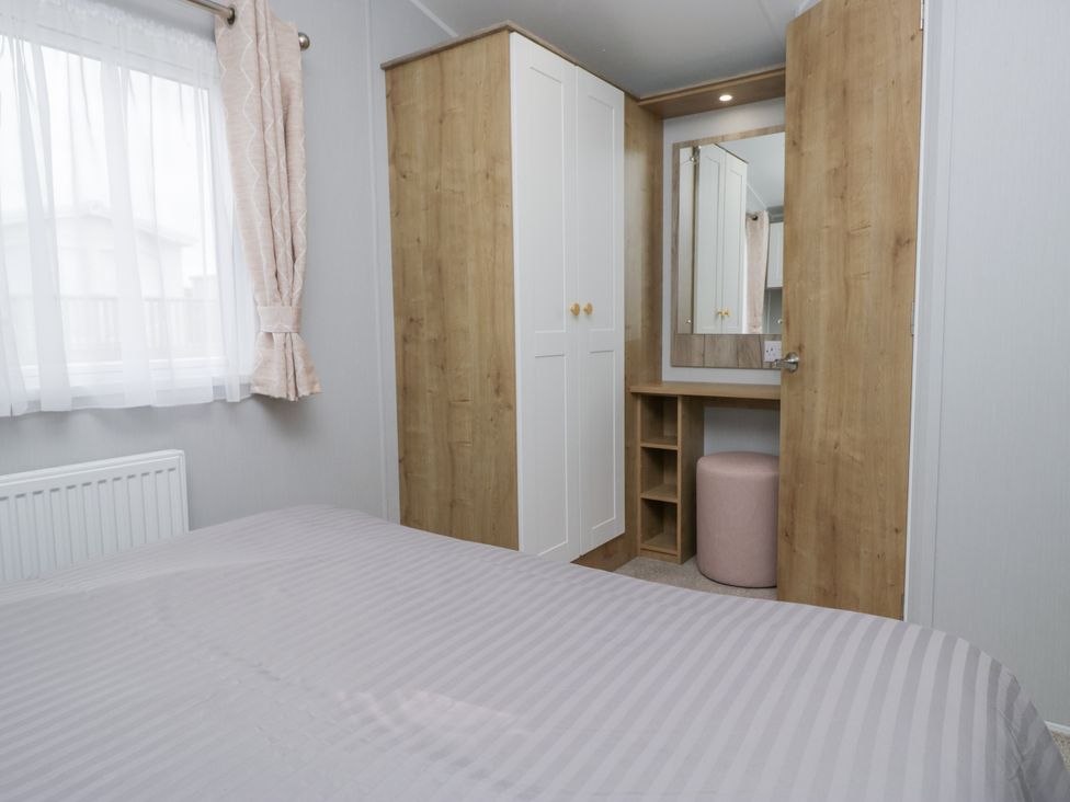 A bedroom with a wardrobe and mirror at Sandpiper in St Bees