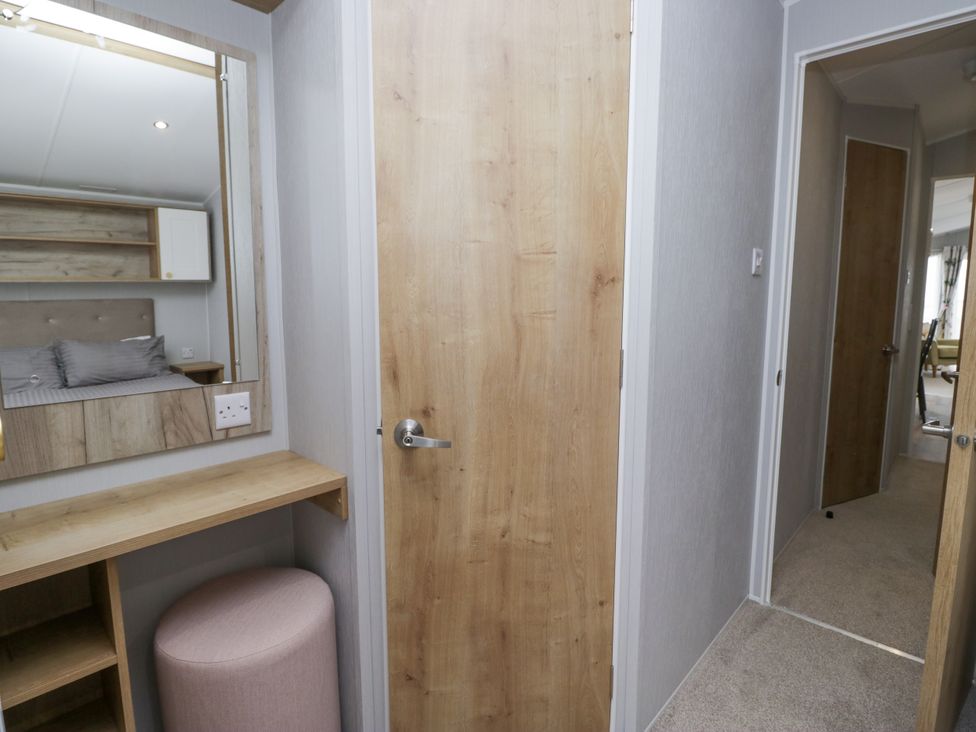 A bedroom with a vanity and mirror at Sandpiper in St Bees