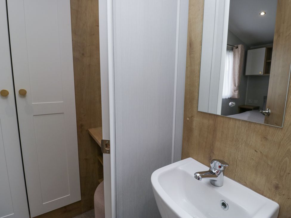 A bathroom with a sink and mirror at Sandpiper in St Bees