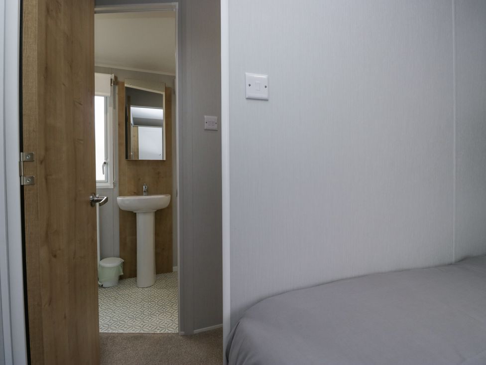 A bathroom with a washbasin and door at Sandpiper in St Bees