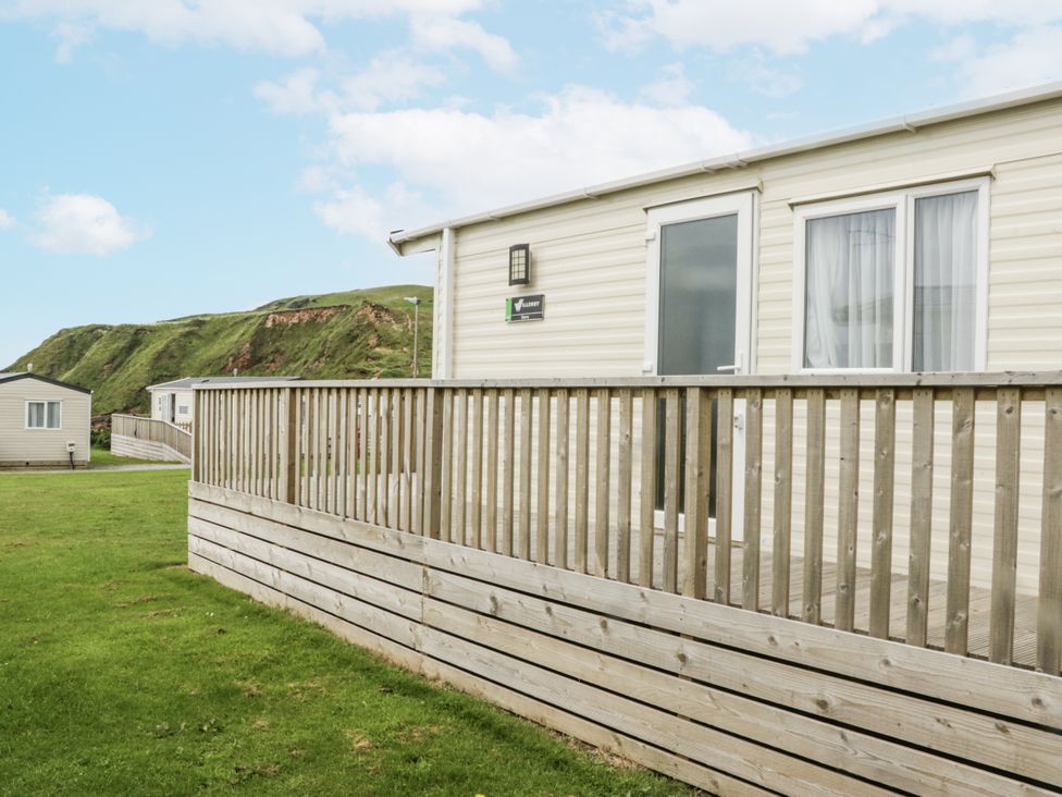 A caravan with decking in an outdoor area at Sandpiper, St Bees