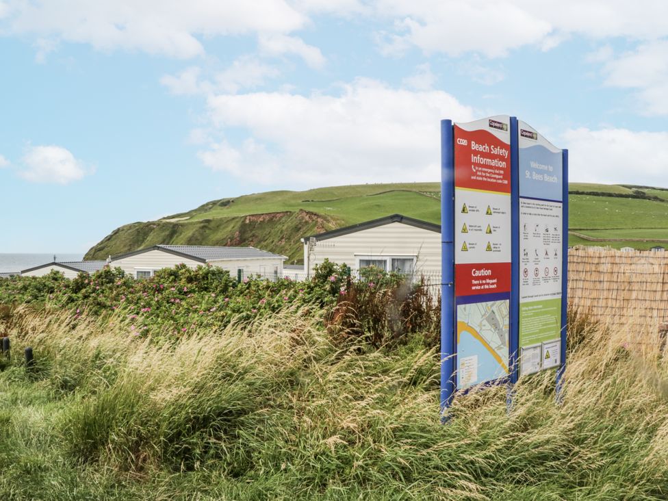 A beach safety information sign with houses in the background at Sandpiper St Bees