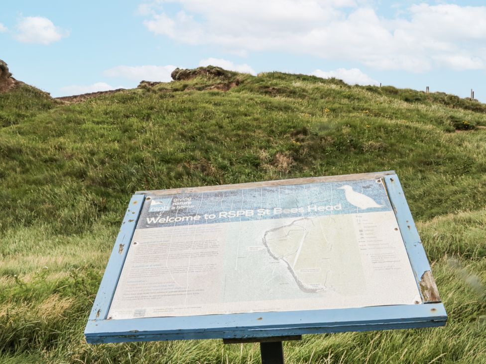 A sign at RSPB St Bees Head with grass and hills in the background