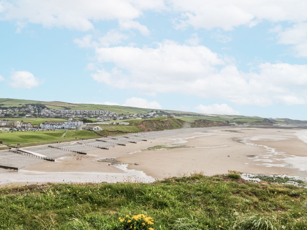 A beach scene with a pier and cliffs at Sandpiper in St Bees