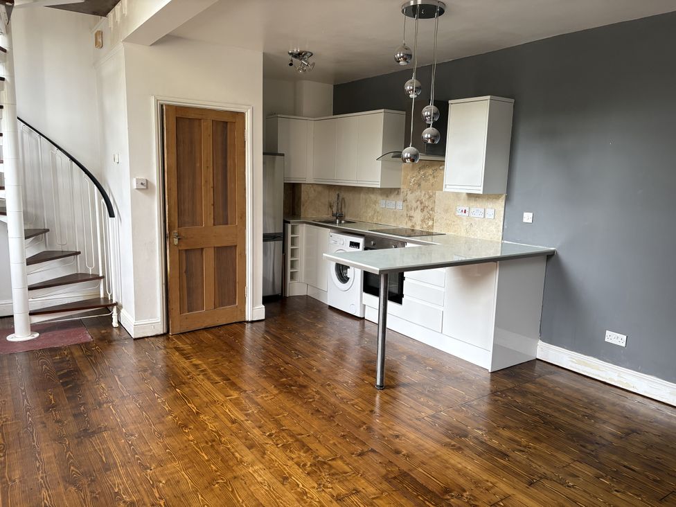 A kitchen with appliances and a spiral staircase at Woolwich Apartment in Woolwich