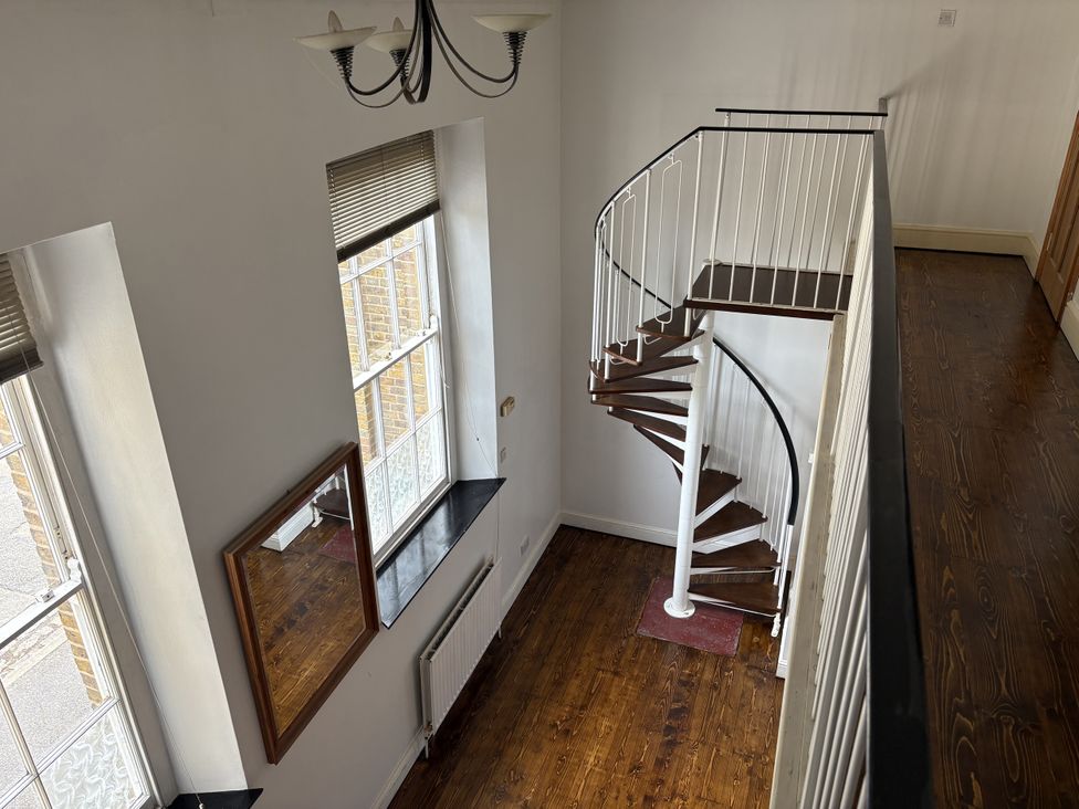 A hallway with a spiral staircase and windows at Woolwich Apartment in Woolwich