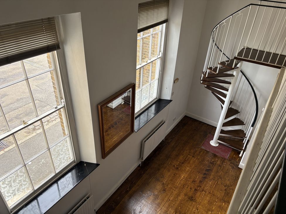A hallway with a staircase and windows at Woolwich Apartment in Woolwich
