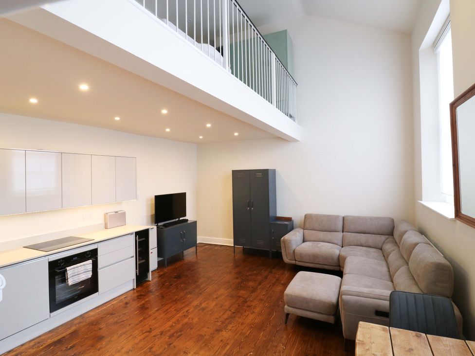 A living room with a kitchen area and a sofa at Woolwich Apartment in Woolwich