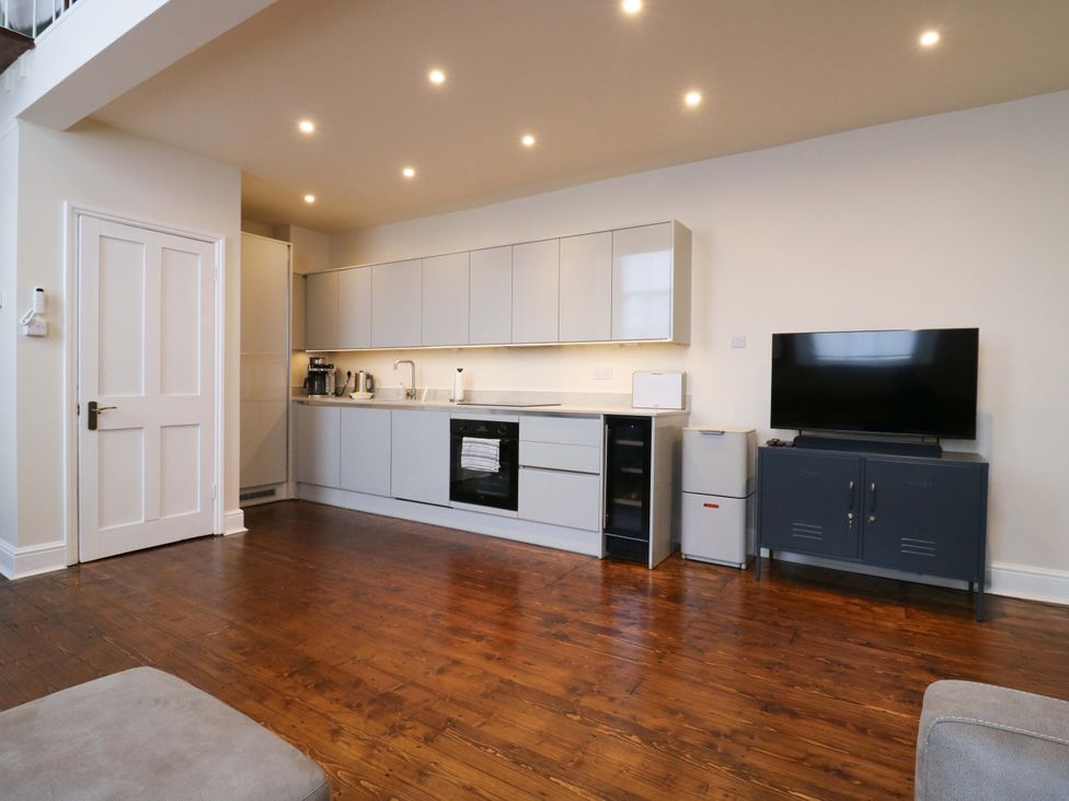 A kitchen with cabinets and a television at Woolwich Apartment in Woolwich