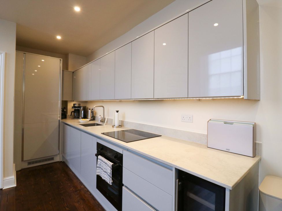 A kitchen with cabinets, countertop, cooktop, and coffee machine at Woolwich Apartment in Woolwich