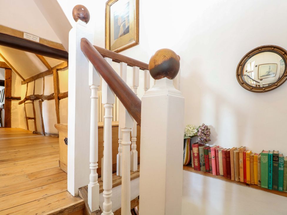 A staircase with books on a shelf and a mirror in a hallway at Bank House