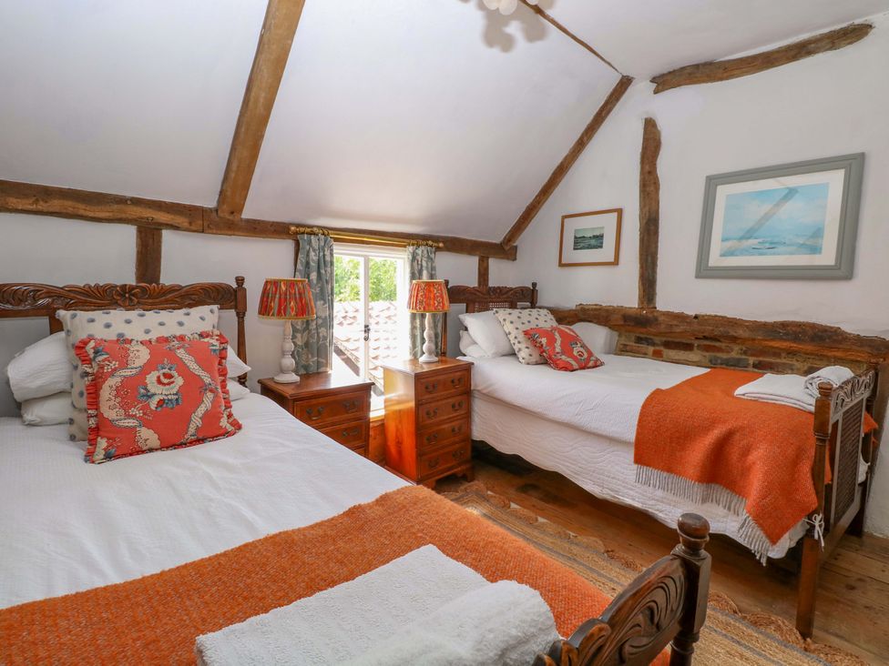 A bedroom with two beds and wooden features at Bank House