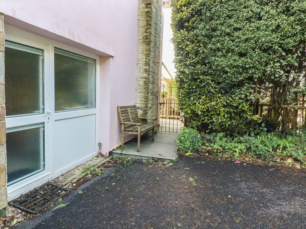 An outdoor area with a bench next to a door at Mini Mena in St Austell