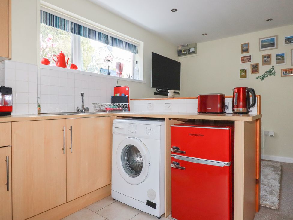 A kitchen with a washing machine and red refrigerator at Mini Mena St Austell