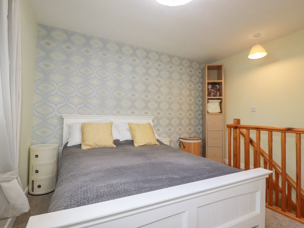 A bedroom with a bed and storage cabinet at Mini Mena in St Austell