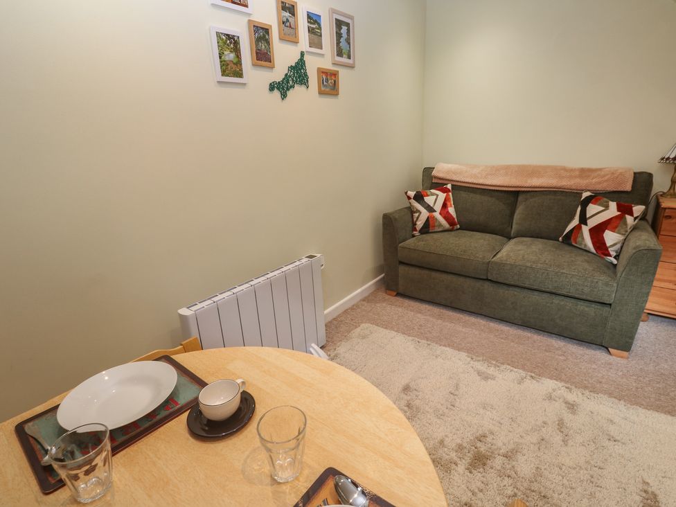 A living room with a sofa and a table set for dining at Mini Mena in St Austell