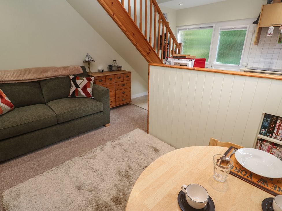 A living room with a sofa and a dining table at Mini Mena in St Austell