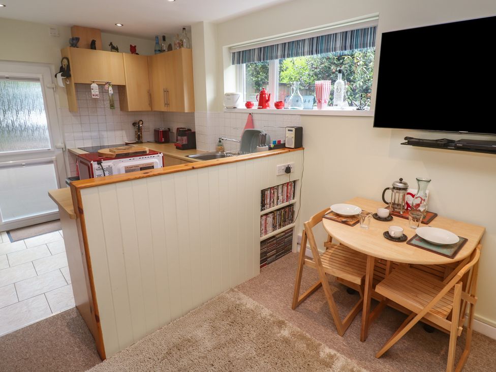 A kitchen with a dining table and TV at Mini Mena in St Austell
