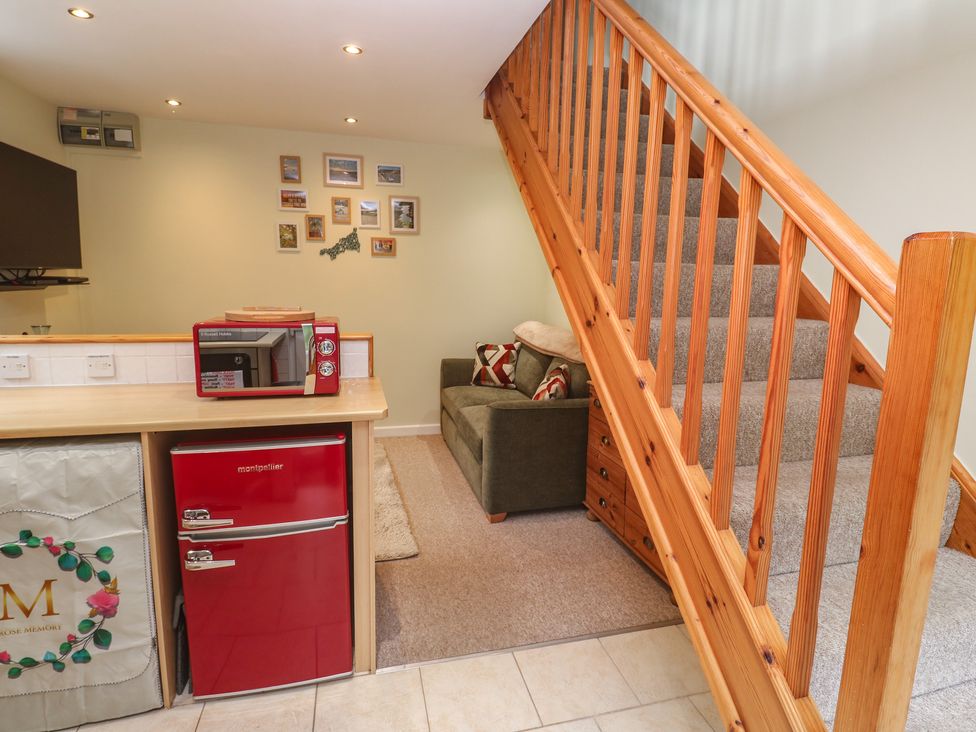 A living room with a staircase and a kitchenette at Mini Mena St Austell