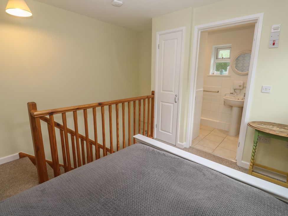 A bedroom with a bed and access to a bathroom at Mini Mena St Austell