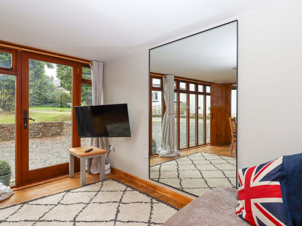 A living room with a television and large window at Church Barn in Sutcombe near Bradworthy