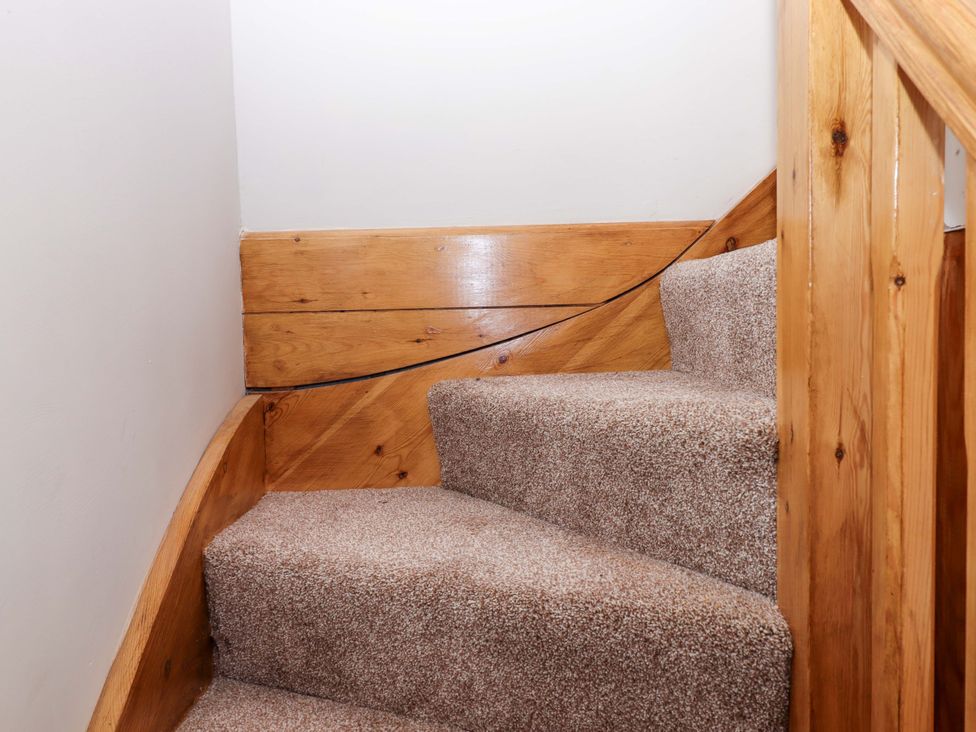 Stairs with carpet and wood railing at Church Barn in Sutcombe near Bradworthy