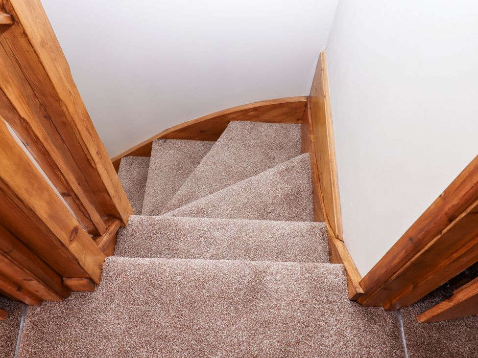 A staircase with carpet and wooden railing at Church Barn Sutcombe near Bradworthy