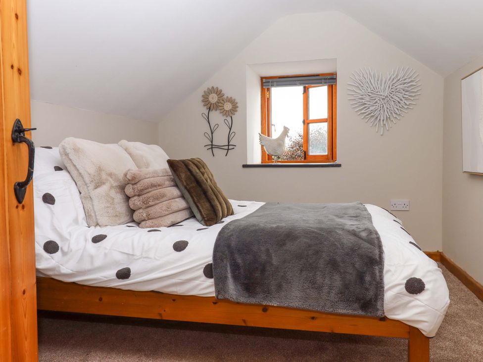 A bedroom with a bed and decorative wall elements at Church Barn Sutcombe near Bradworthy
