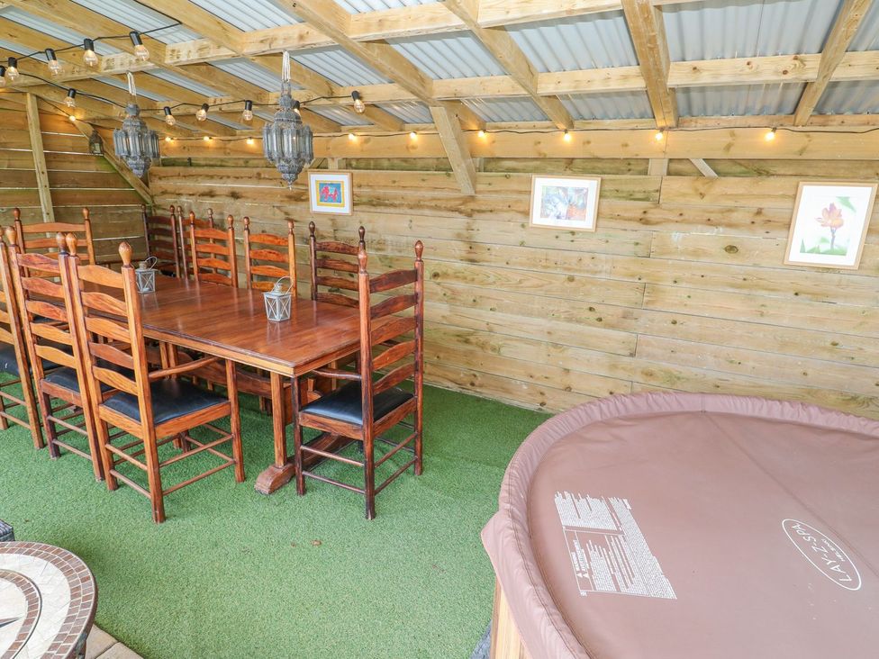 A dining area with wooden table and chairs and a hot tub at Five Elements Barn in Truro