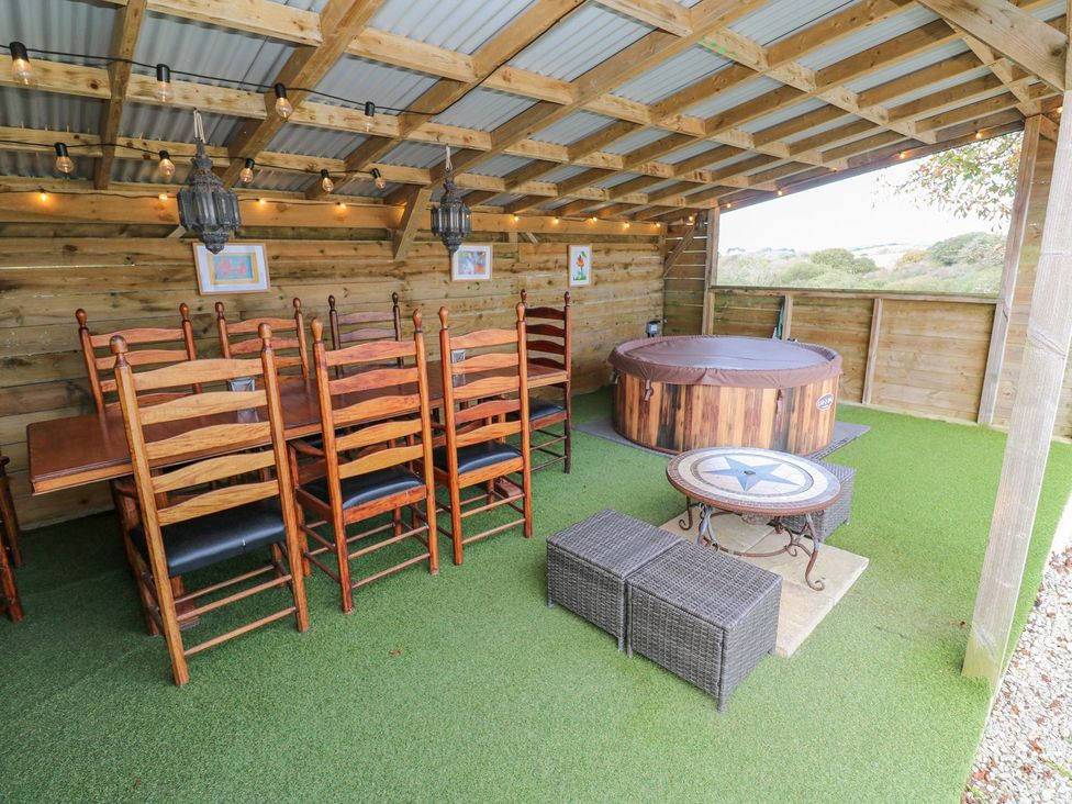 An outdoor area with a dining table, chairs, and a hot tub at Five Elements Barn in Truro