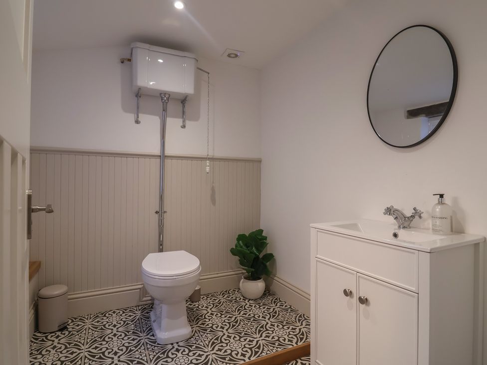 A bathroom with a toilet, sink, and mirror at 46 North Street, Stoke-Sub-Hamdon, Somerset
